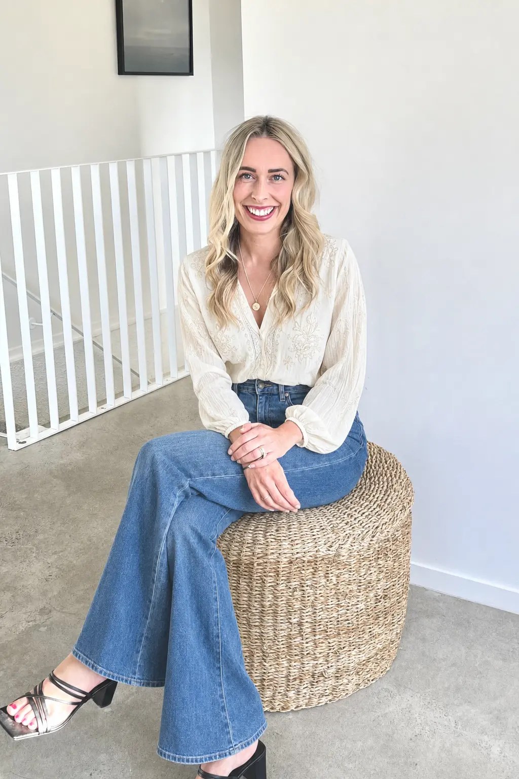 Aimee, founder of The Alignment Collective in Hamilton, sitting on a woven stool in a bright studio, smiling